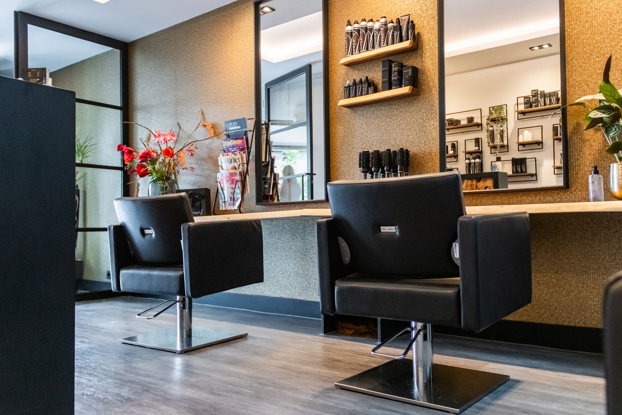 Twee zwarte kappersstoelen voor grote spiegels in de salon